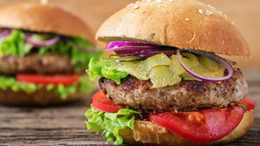 Χάμπουργκερ με ντομάτα, φύλλα σαλάτας και αγγουράκια τουρσί