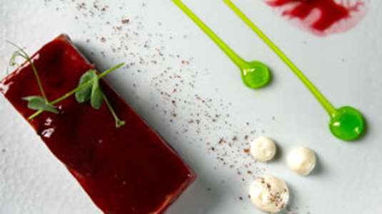 Αρνάκι στη γάστρα πρεσαριστό, με κρέμα τραχανά, σάλτσα από πατζάρι και τσιπς από φιστίκια Αιγίνης